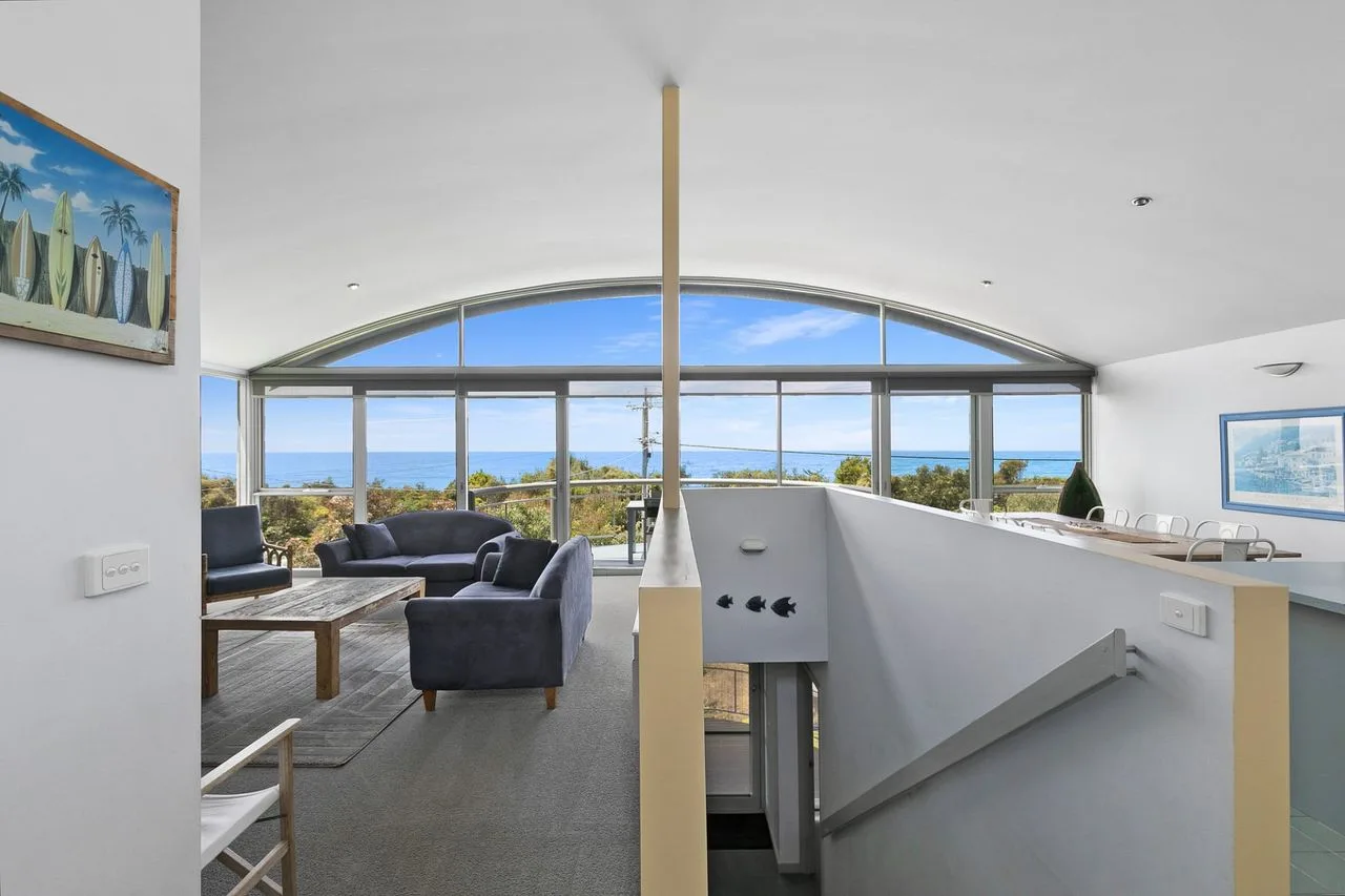 An open living and dining area faces a wide window with ocean views.