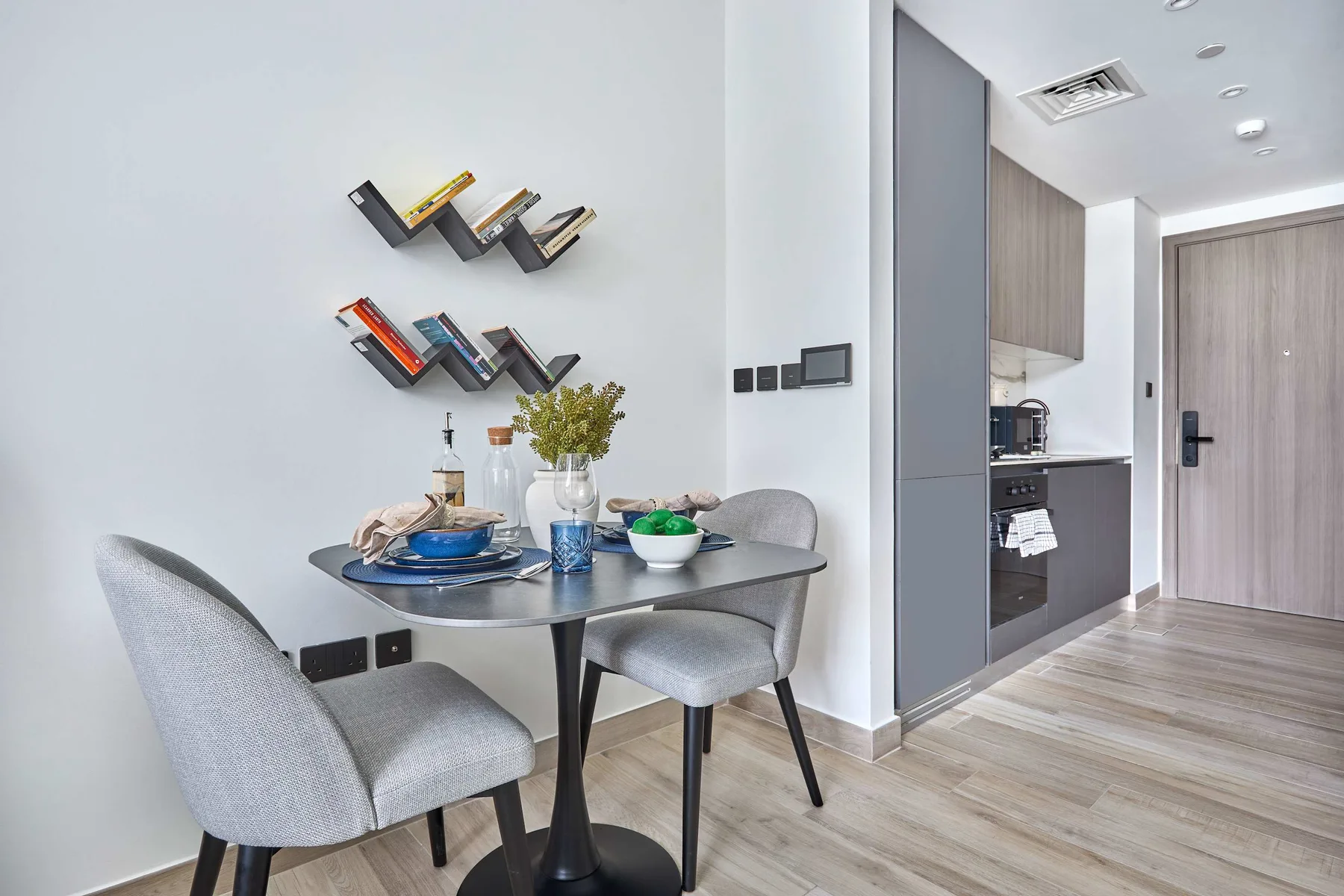 Comedor con una mesa redonda y sillas junto a una cocina compacta.