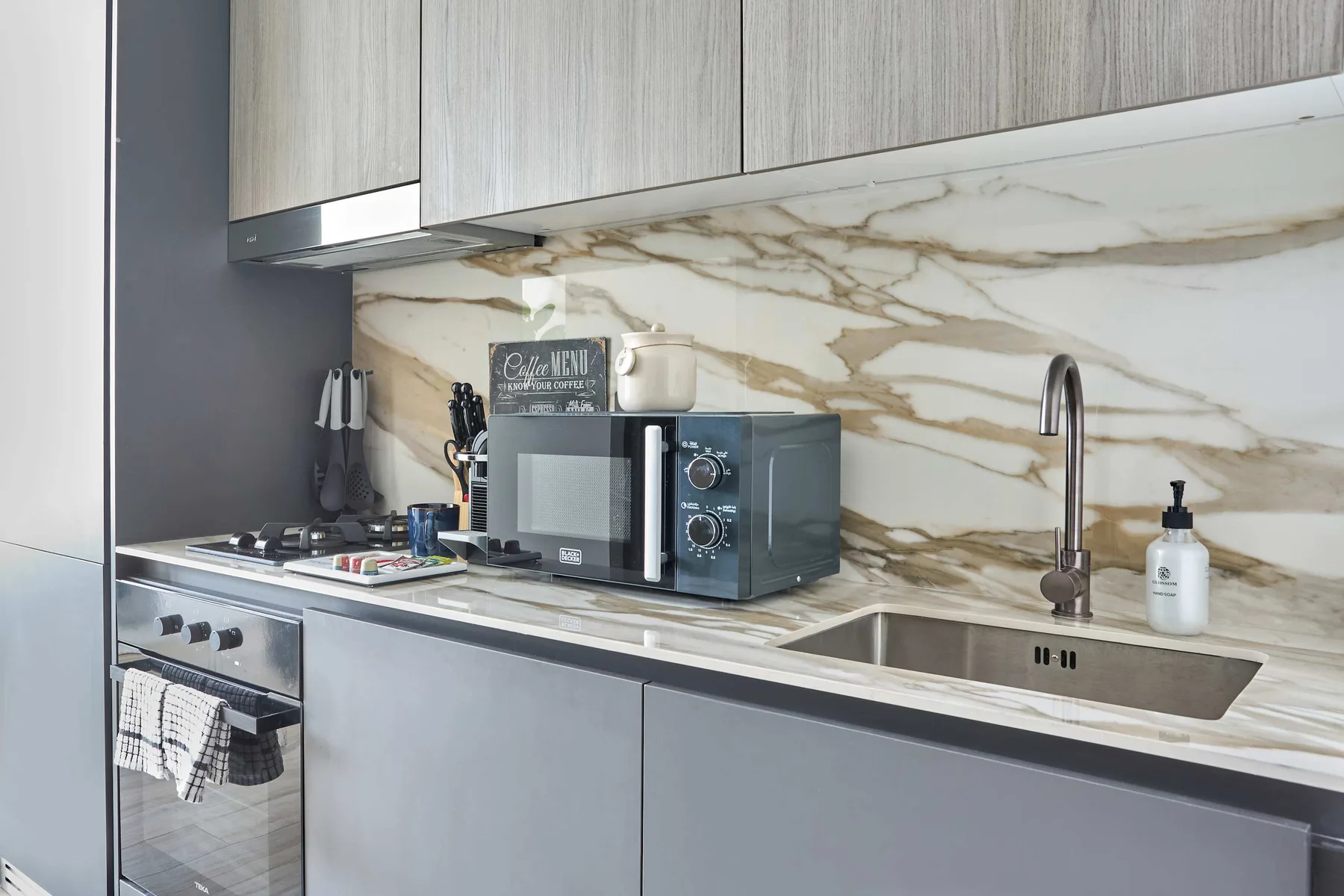 A modern kitchen with a microwave on the counter and a sink.