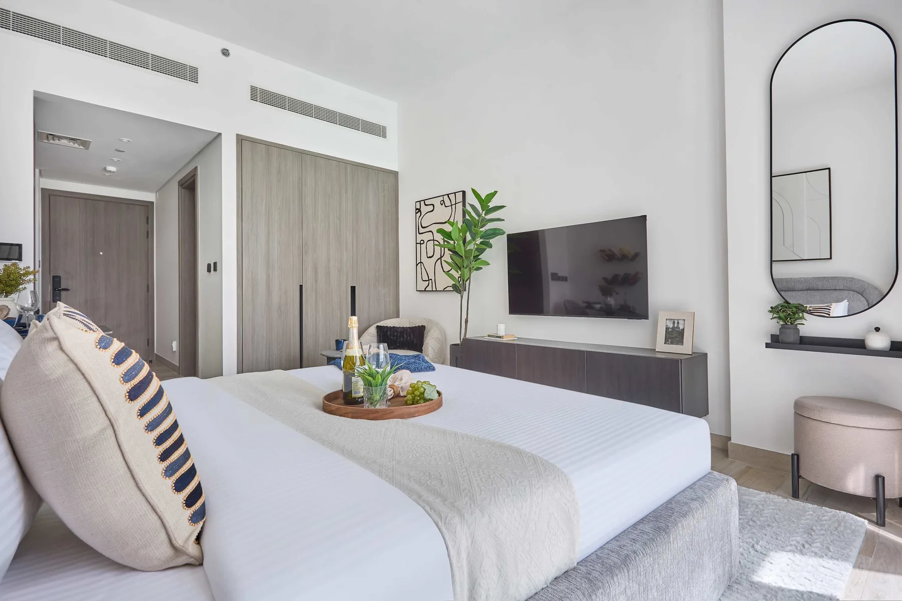 A bedroom with a neatly made bed and a television mounted on the wall.