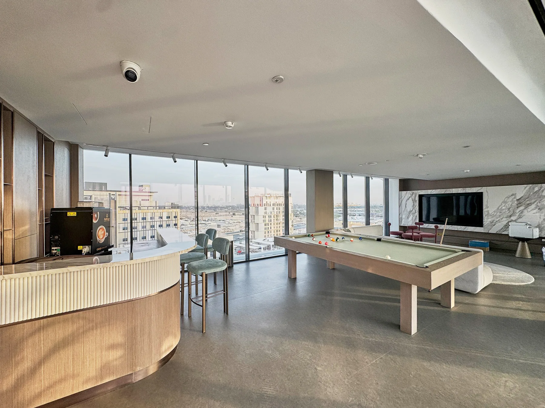 A bright game room with a pool table and floor-to-ceiling windows.