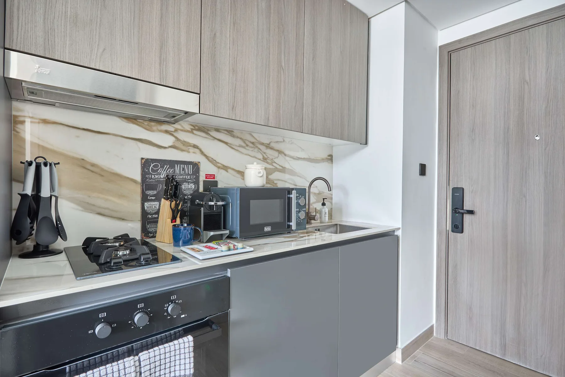 A compact kitchen with gray cabinets, a cooktop, and countertop appliances.