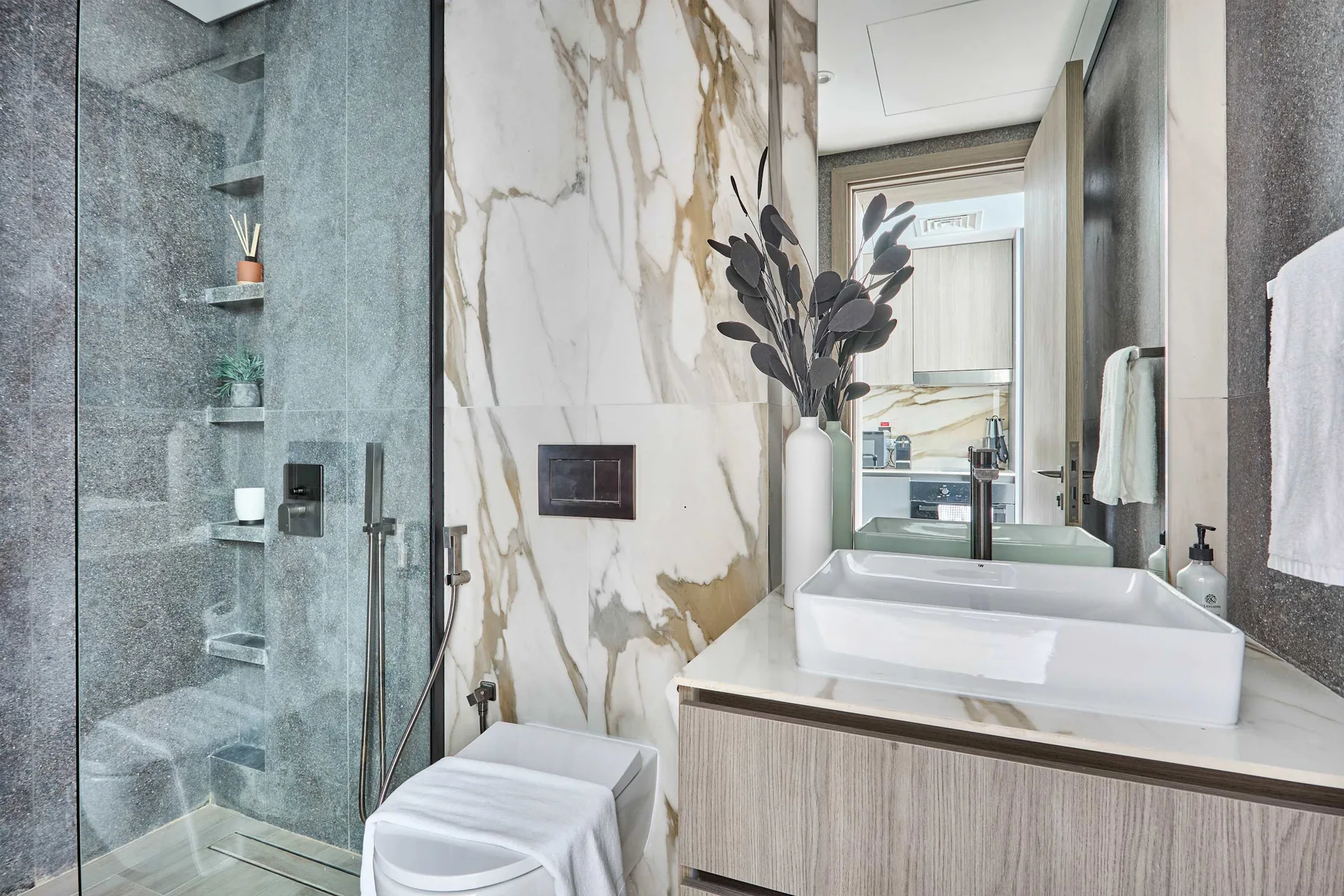 A modern bathroom with a glass shower and a wide vanity topped by a sink.