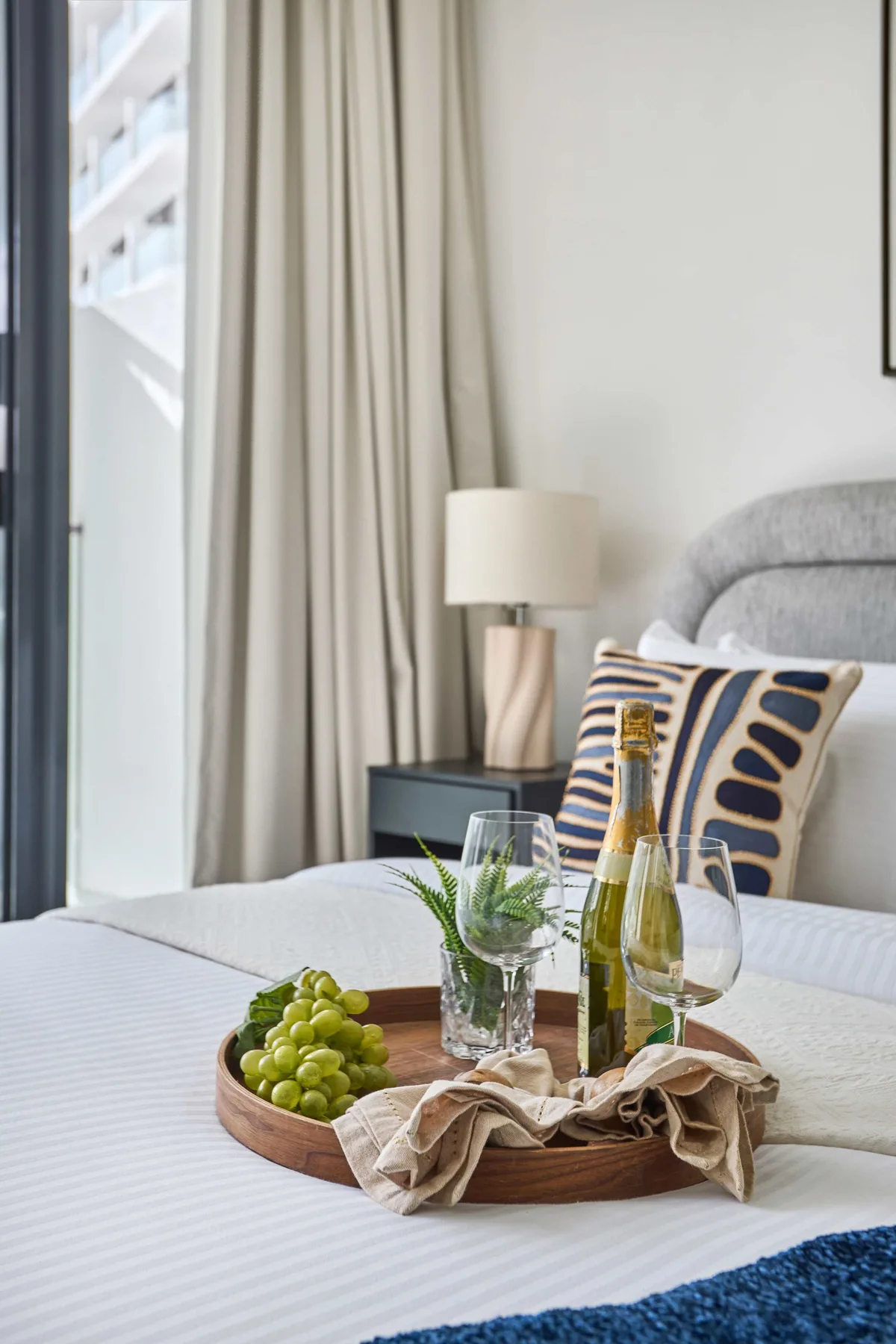 A bedroom with a bed and a tray of fruit and drinks.