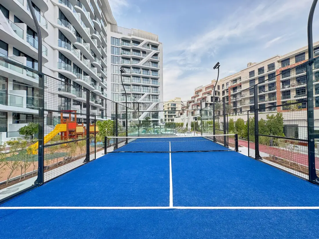 A blue court sits between modern apartment buildings.