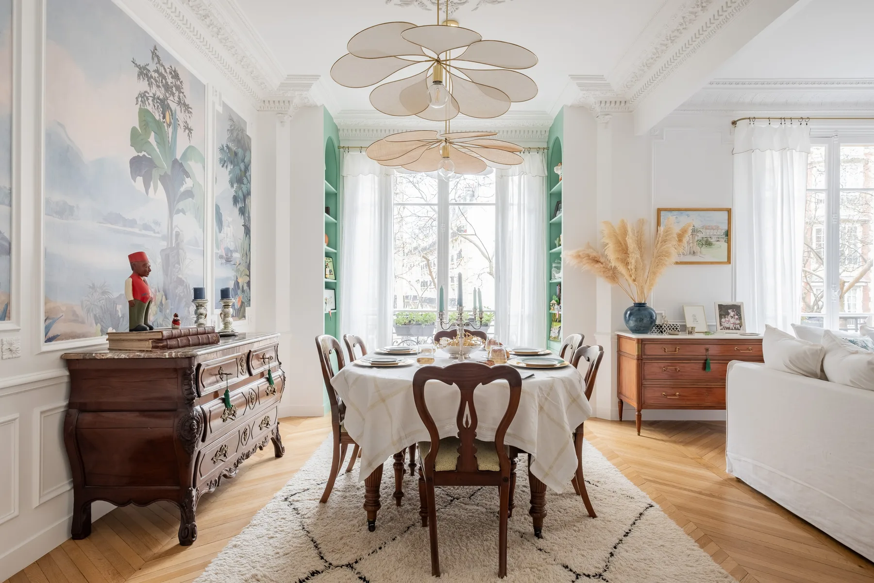 A bright dining room with a long table beneath a decorative ceiling light.