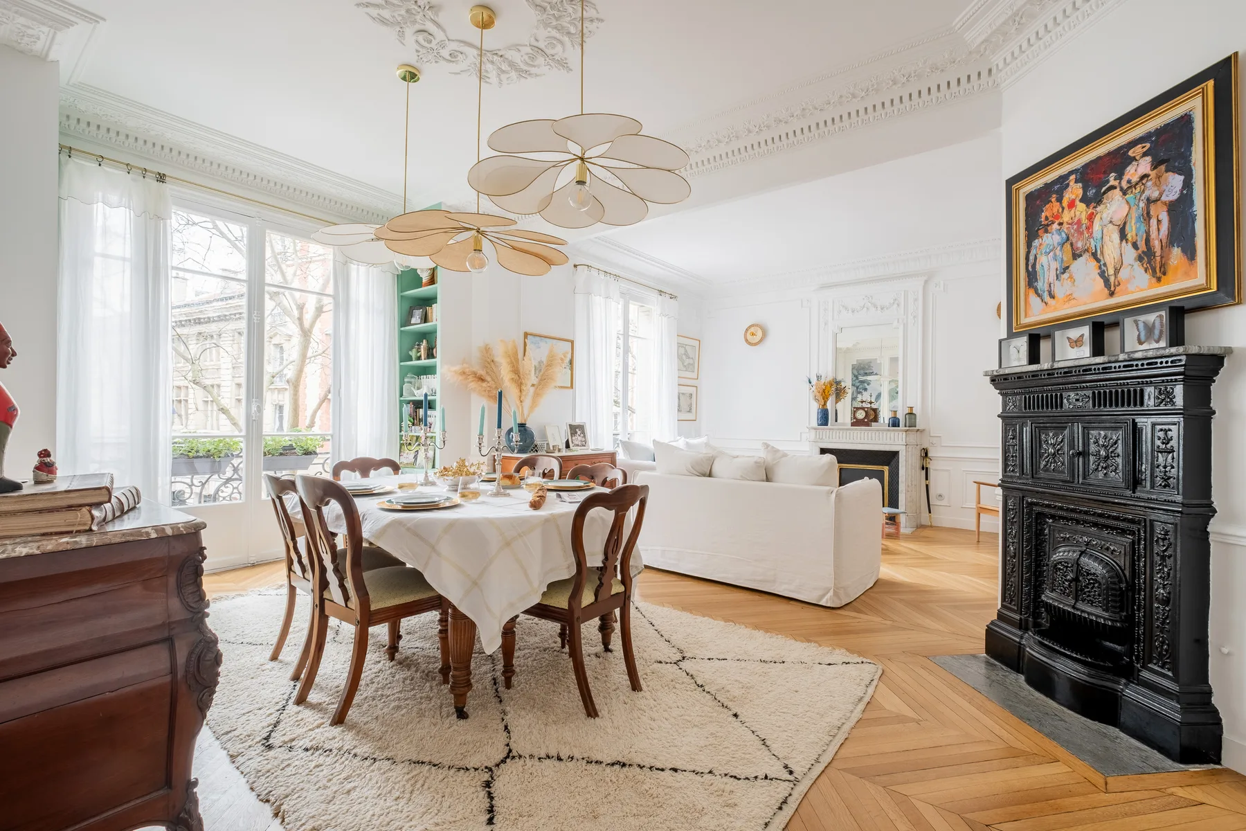 A bright living and dining room with a table set beside large windows.