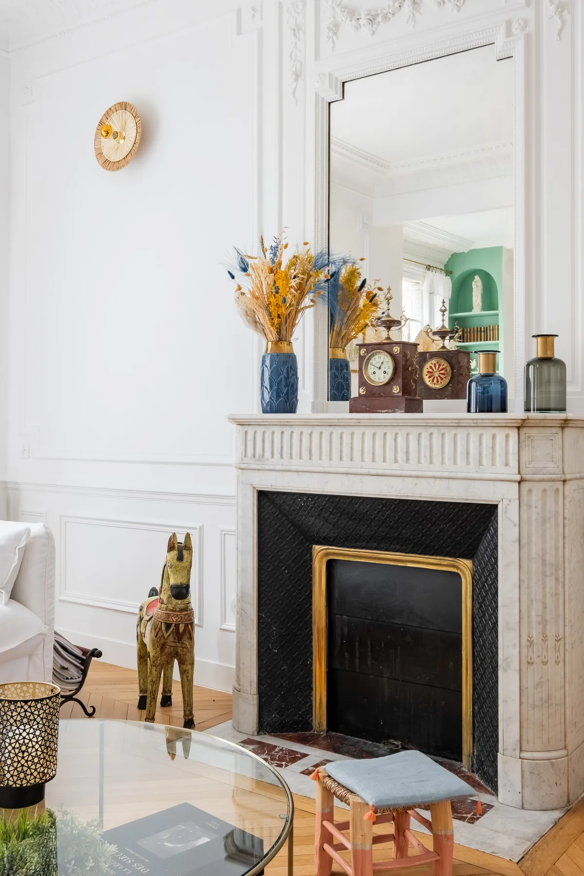 A bright living room features a fireplace with vases and dried flowers on the mantel.