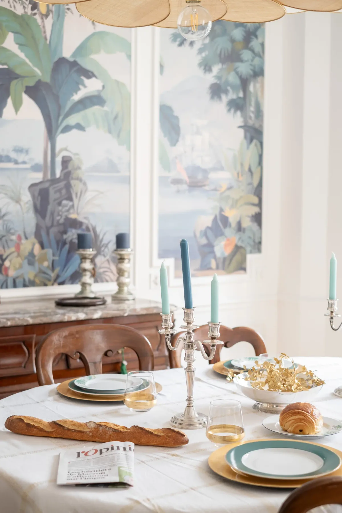 A dining room with a set table and large botanical wall art.