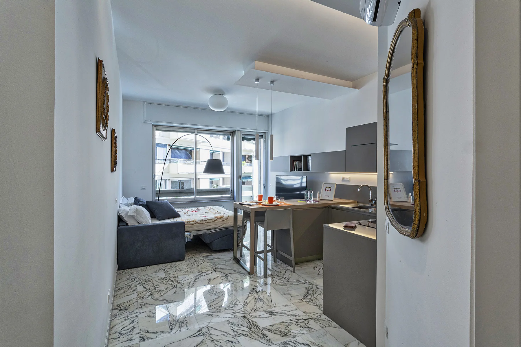Una habitación diáfana con cama, zona de estar y cocina pequeña.