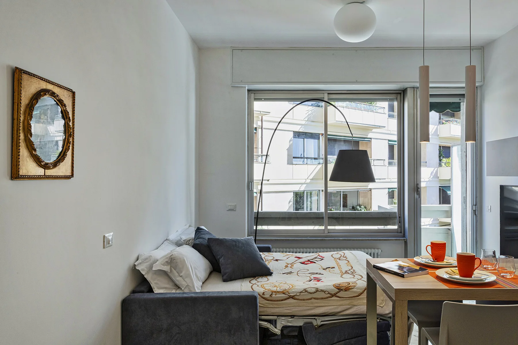 Una pequeña zona de estar y dormir con una cama junto a una mesa de comedor.