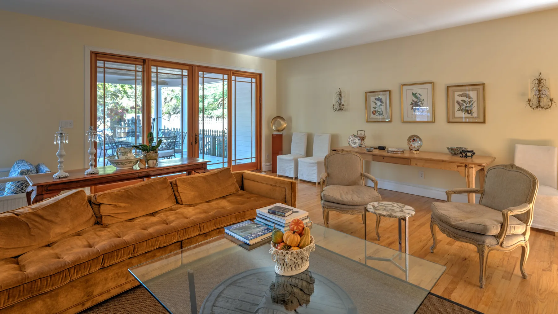 A living room with seating, a glass coffee table, and large windows.