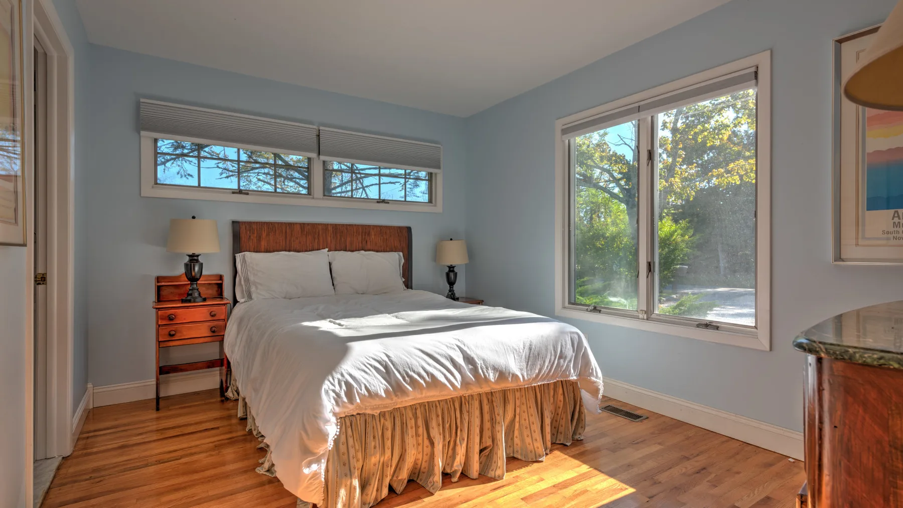 A bedroom with a bed between two bedside tables and windows.