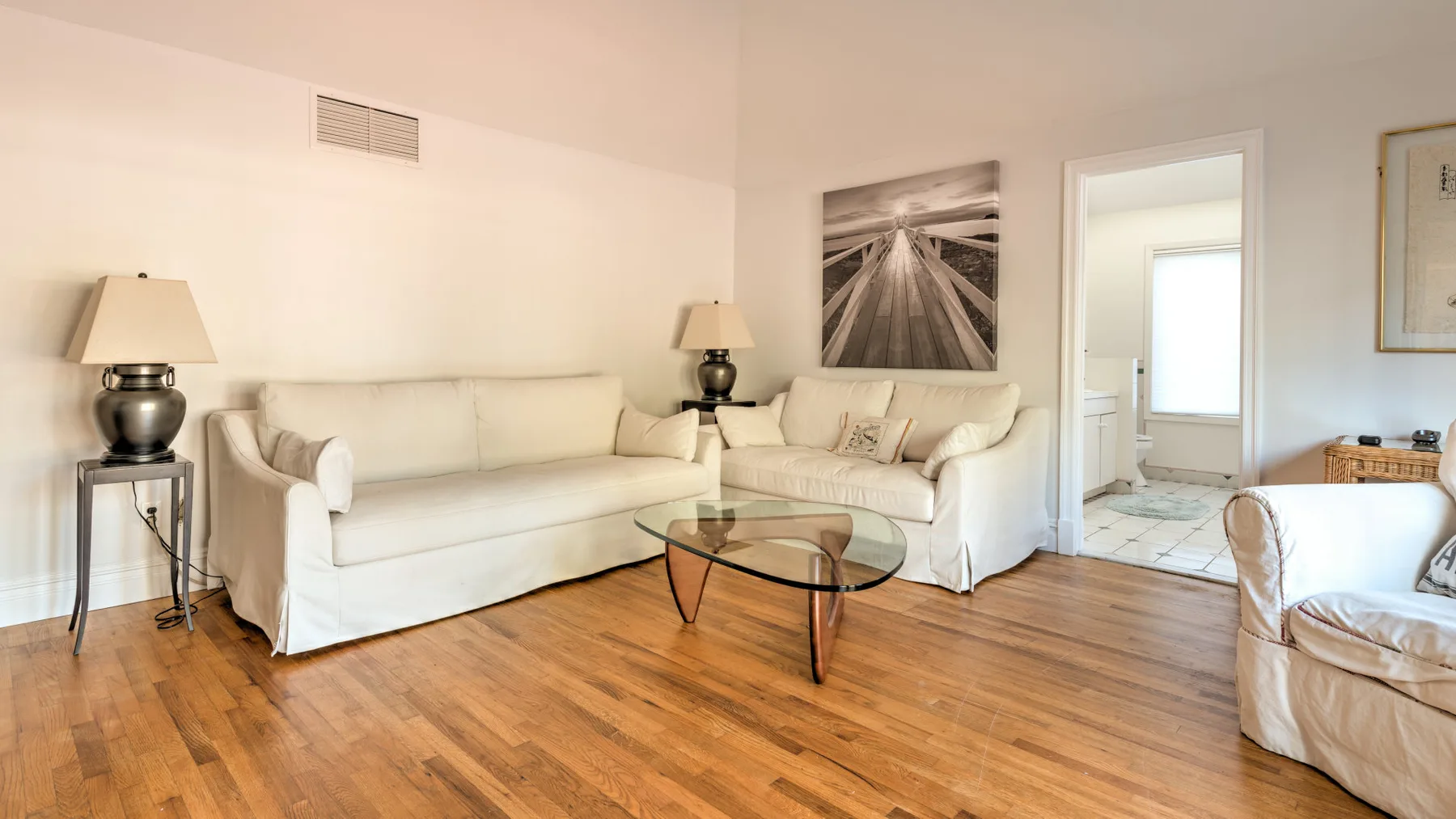 A bright living room with cream seating and a glass coffee table.