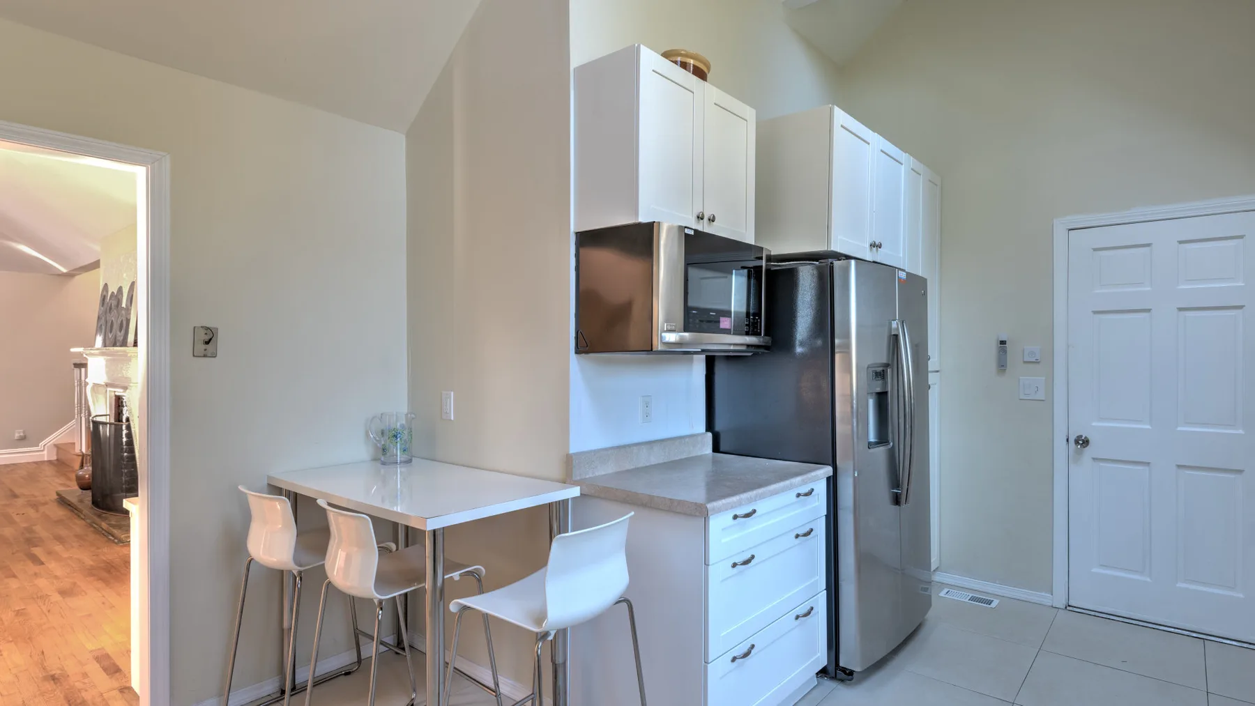 A kitchen with white cabinets, stainless steel appliances, and a small counter with seating.