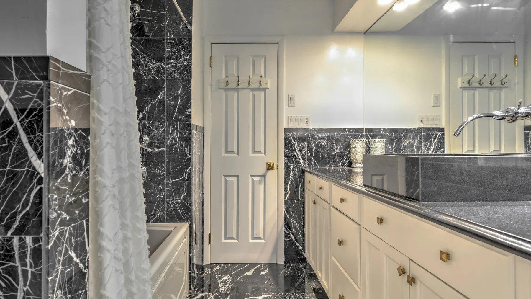 A bathroom vanity with a wide mirror and a bathtub beside a shower curtain.