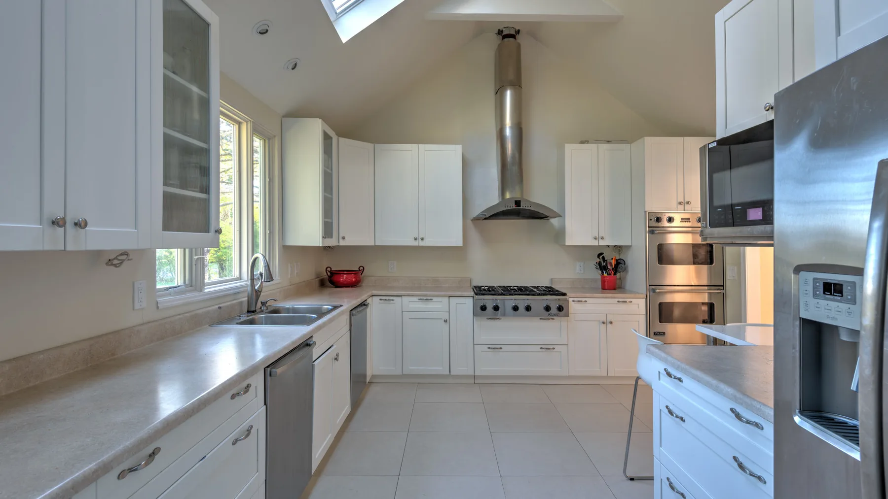 A bright kitchen with white cabinets, wide counters, and stainless steel appliances.