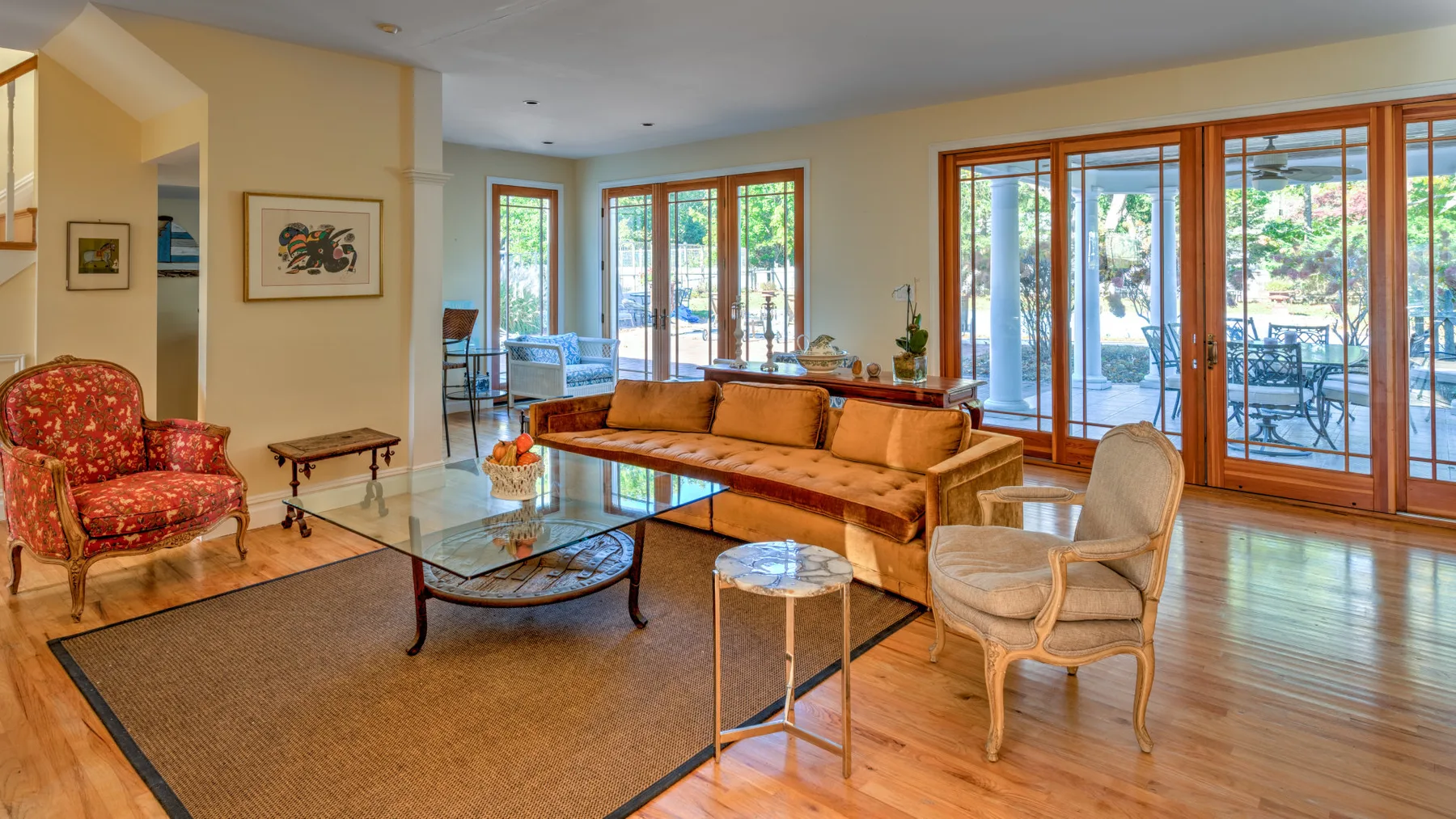 A living room with seating, a glass coffee table, and large windows.