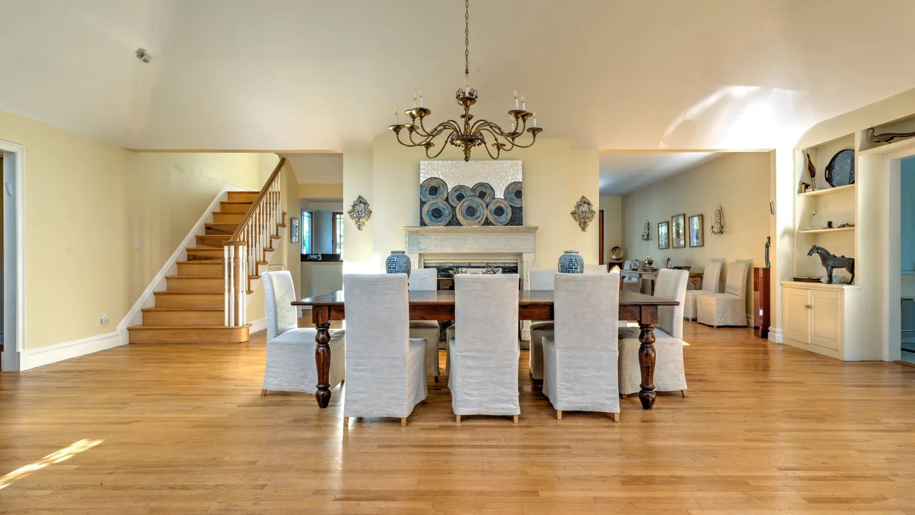 A dining room with a long table and chairs beneath a chandelier.