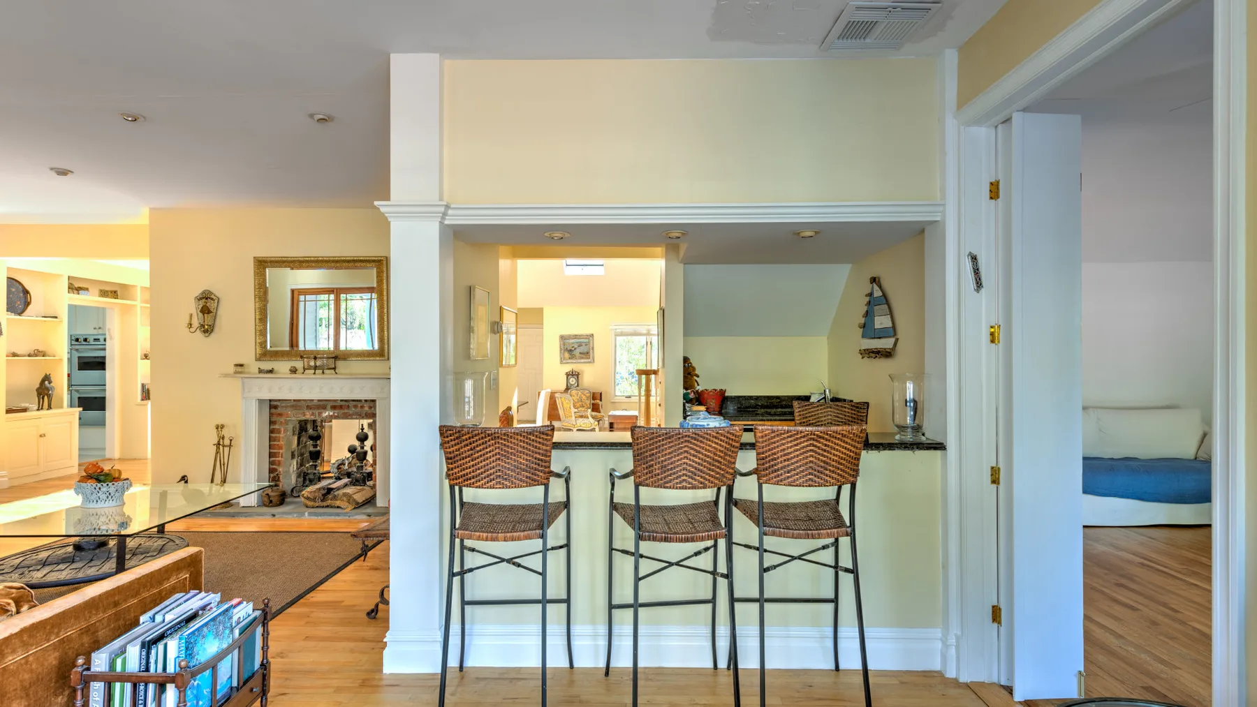 A kitchen counter with bar seating opens onto a living area.