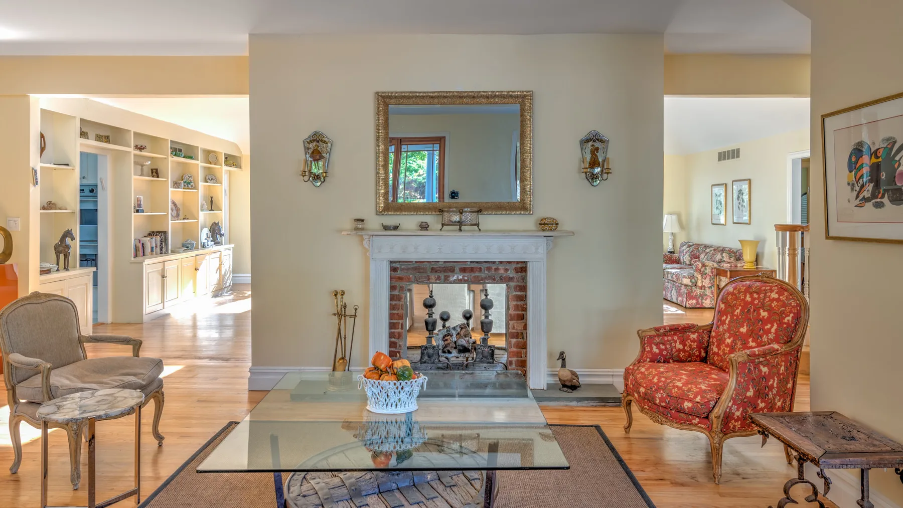 A living room with a fireplace, glass coffee table, and seating.