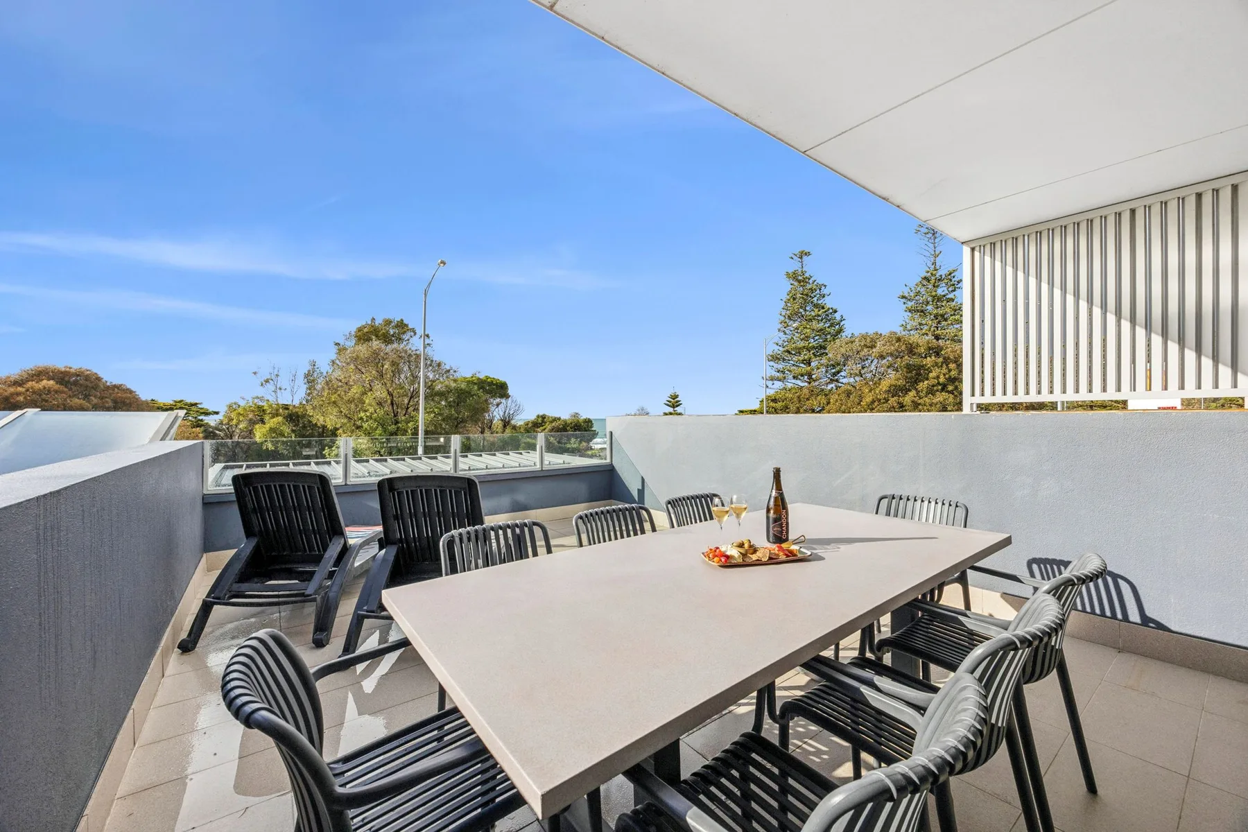 Una terraza de comedor al aire libre con una mesa larga y asientos alrededor.