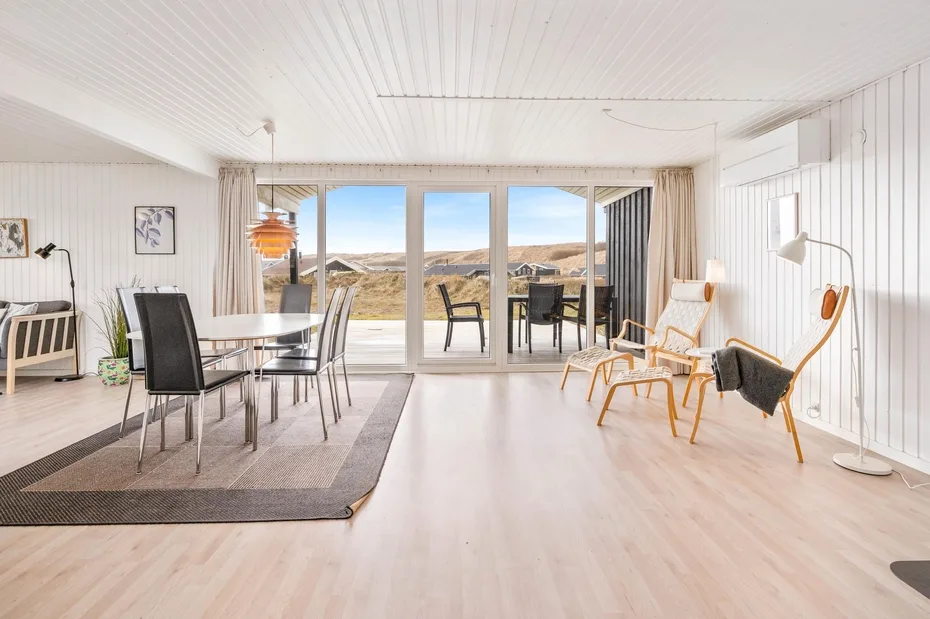 Una luminosa sala de estar y comedor da a un patio, con un amplio paisaje al fondo.