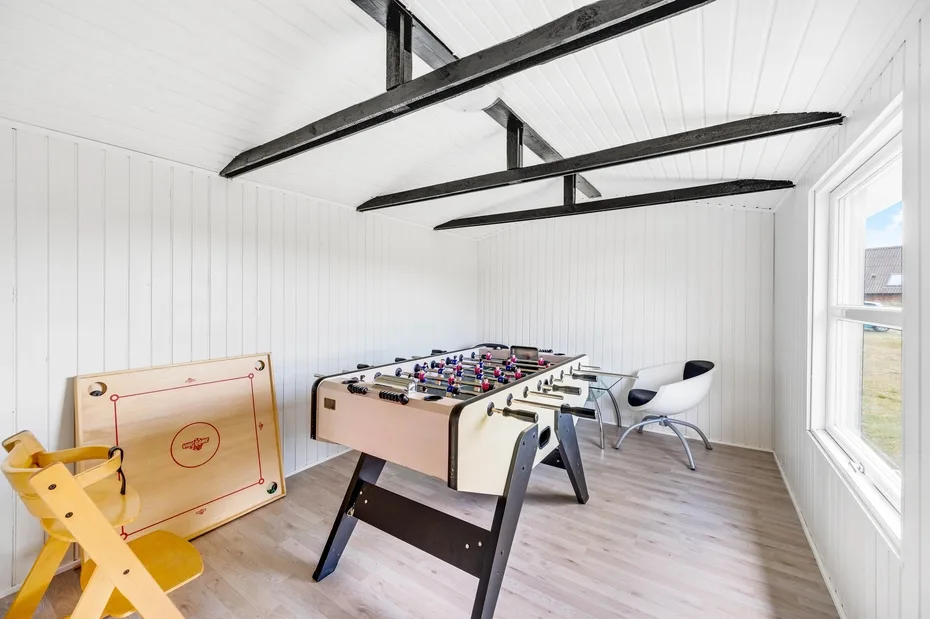 Una luminosa sala de juegos con una mesa de futbolín y un juego de tejo de mesa.