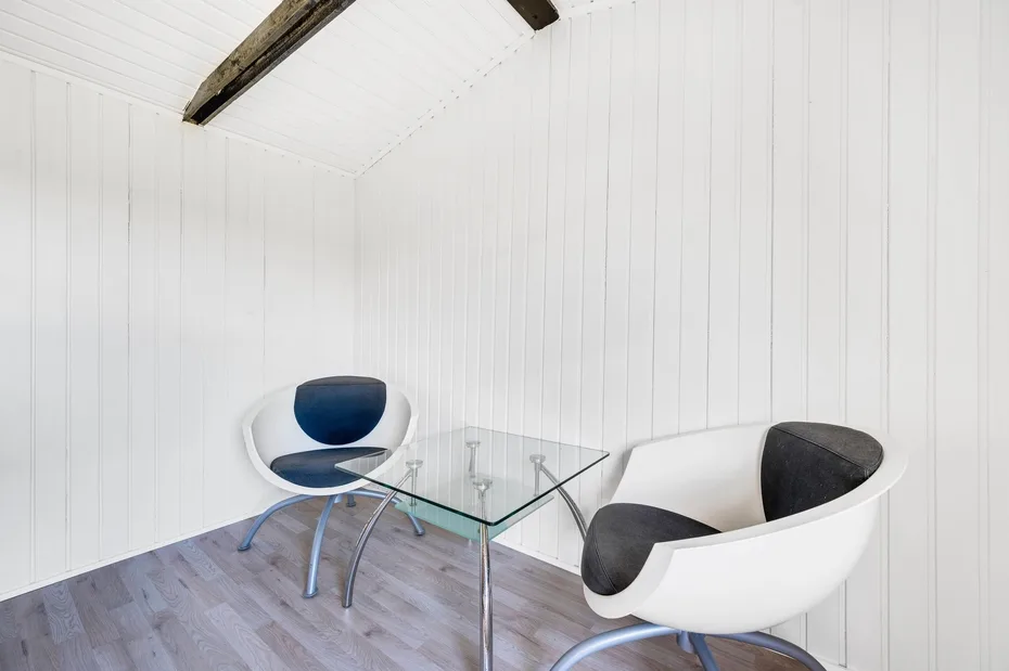 Una luminosa zona de estar con dos sillones modernos y una mesa de vidrio.