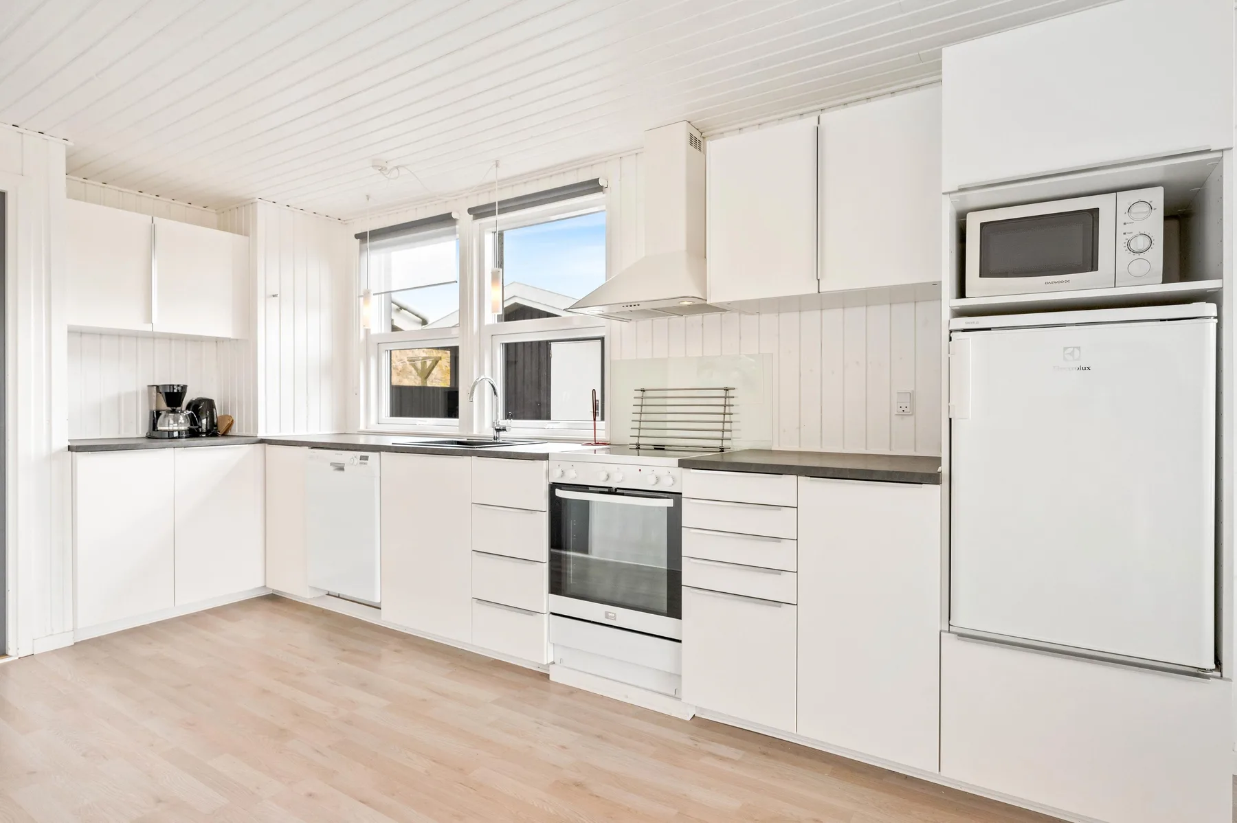 Una cocina luminosa con gabinetes blancos, horno y refrigerador.