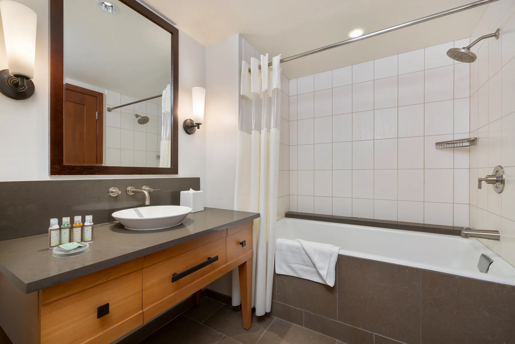 Un baño con un lavabo junto a una bañera alicatada con ducha.
