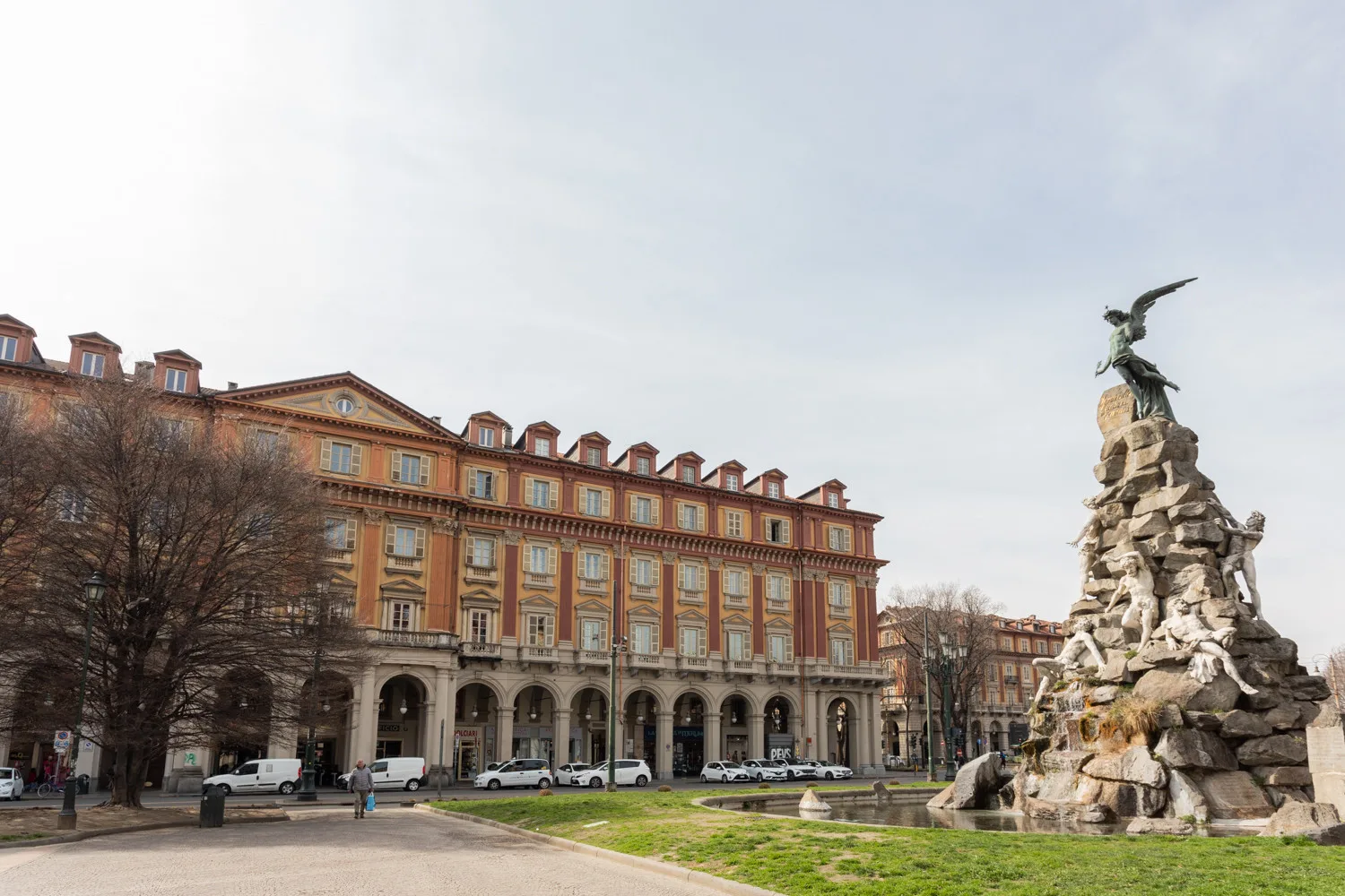 A large historic-looking building stands beside a stone monument in an open plaza.