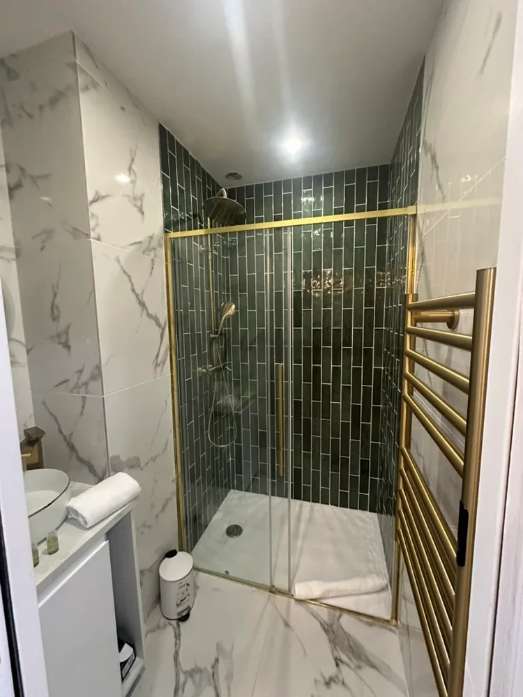 A tiled bathroom with a glass-enclosed shower and a towel rail.