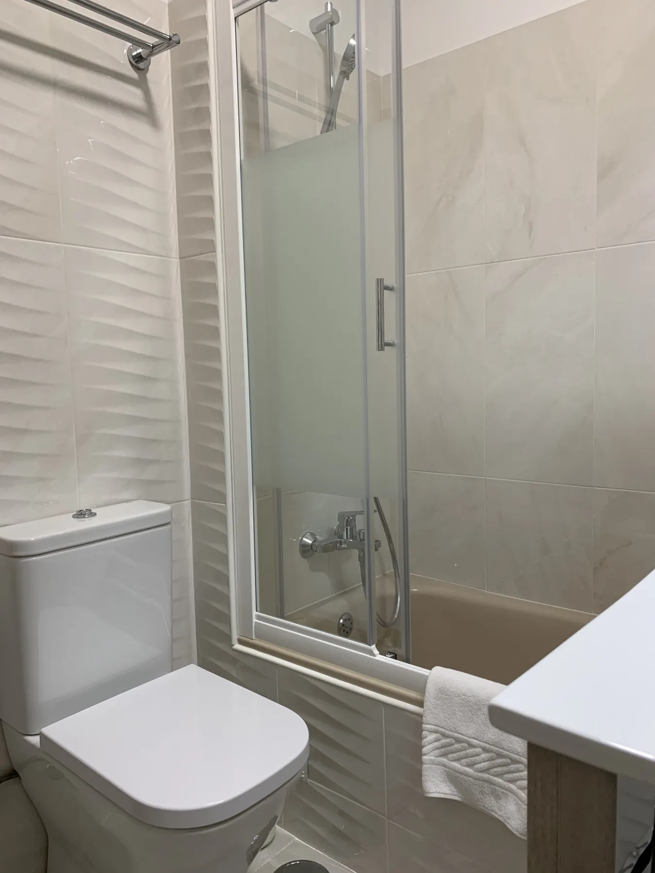 Un baño con ducha, inodoro y toalla.