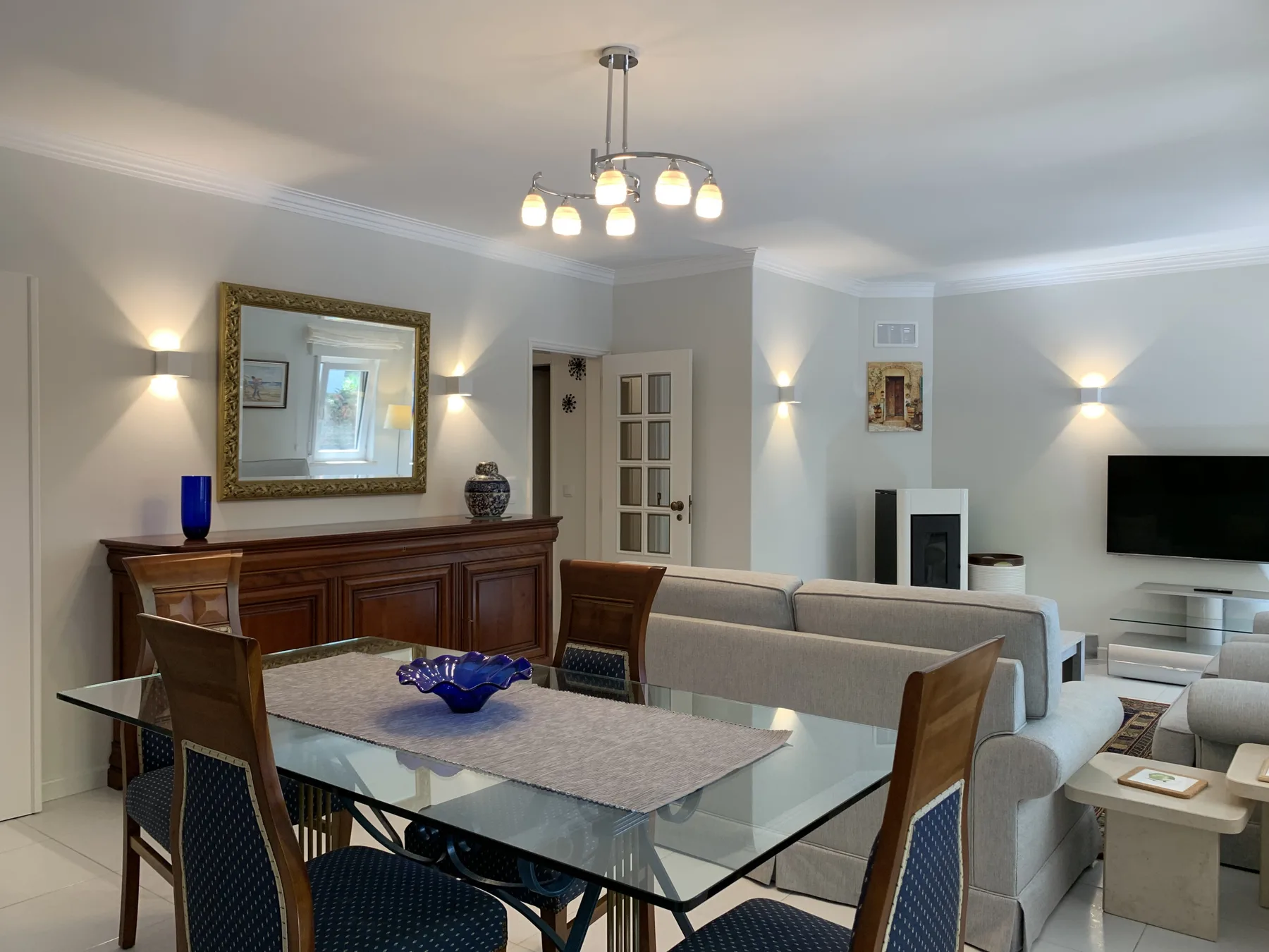 Sala de estar y comedor con una mesa de comedor de vidrio y asientos.