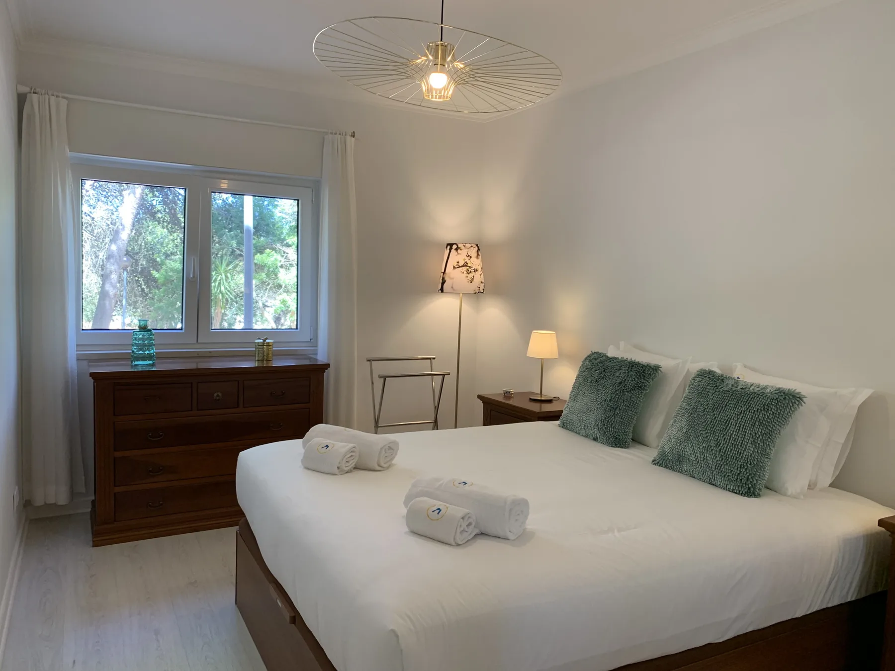 Un dormitorio con una cama bien hecha y una ventana con vistas a la vegetación.