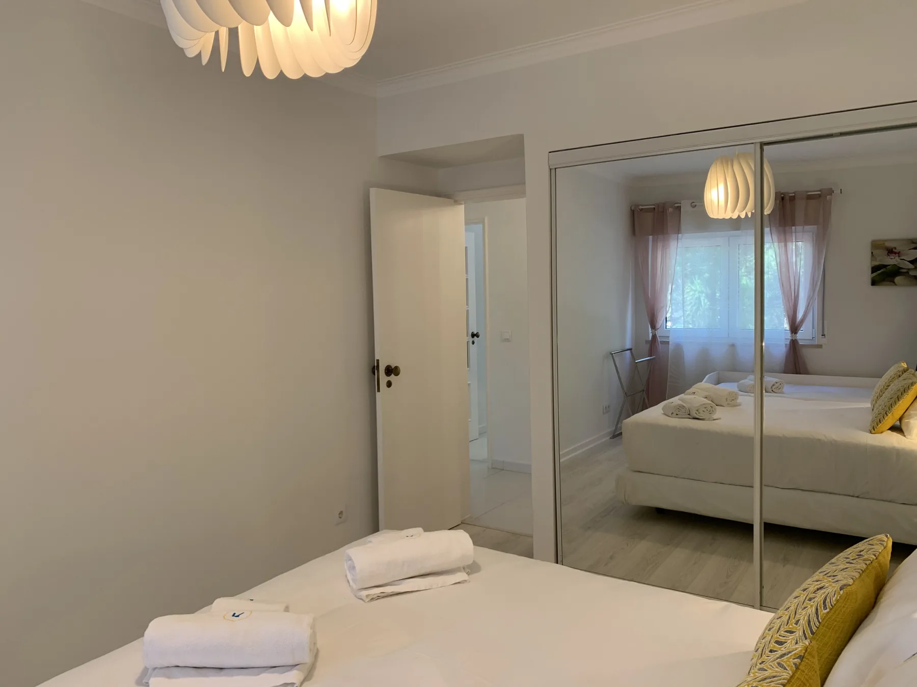 Un dormitorio con una cama, toallas dobladas y puertas de armario con espejo.