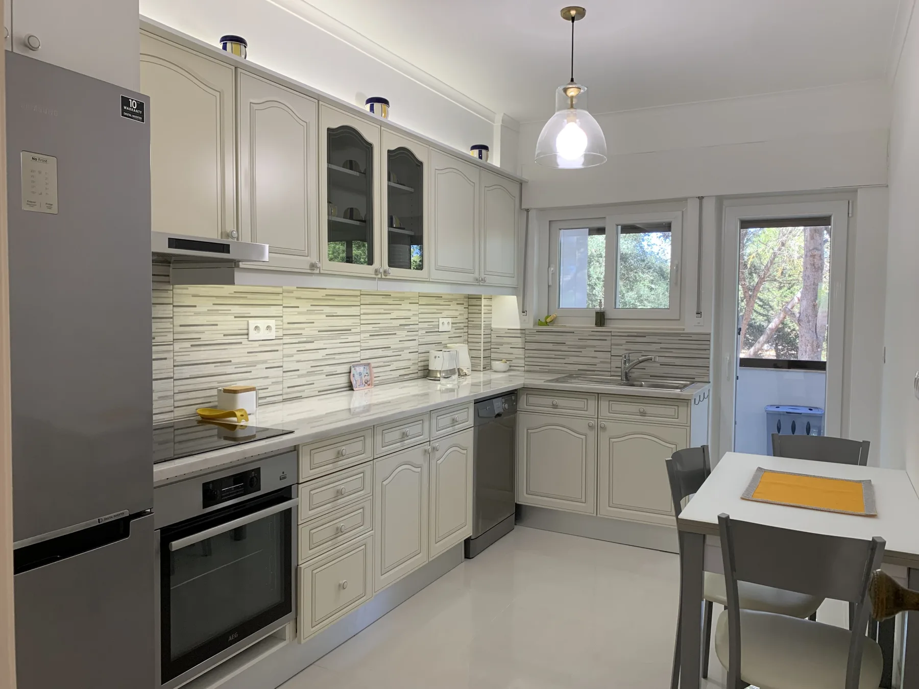Cocina luminosa con armarios claros, un salpicadero de azulejos y una mesa de comedor.