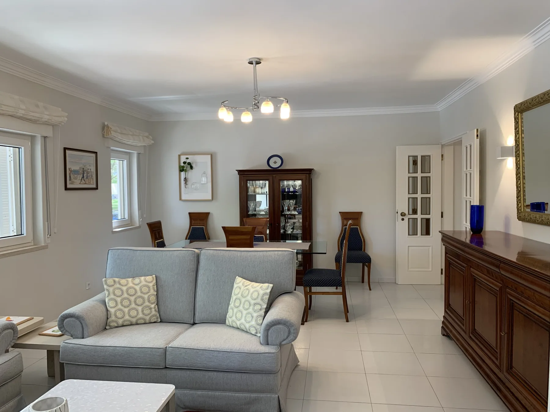 Sala de estar y comedor con un sofá gris y un mueble de madera.