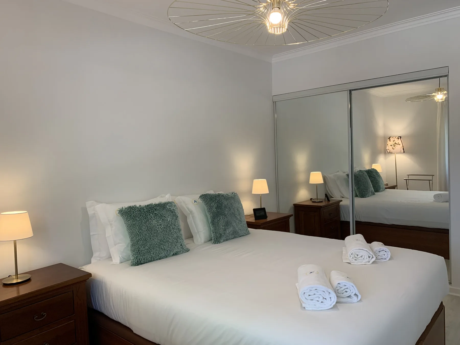 Un dormitorio luminoso con una cama bien hecha y puertas de armario con espejo.