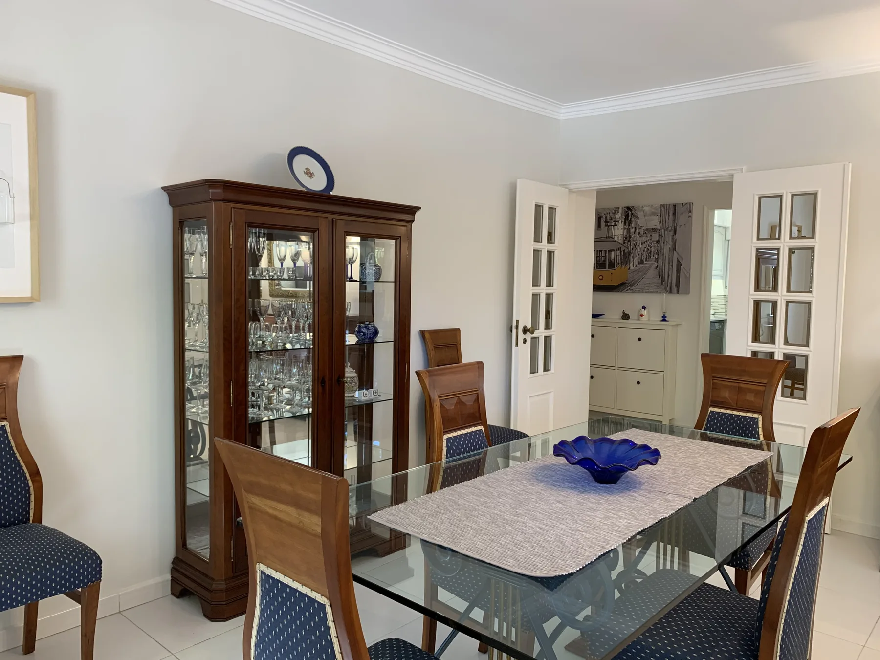 Comedor con una mesa de vidrio y una vitrina con puertas de vidrio.
