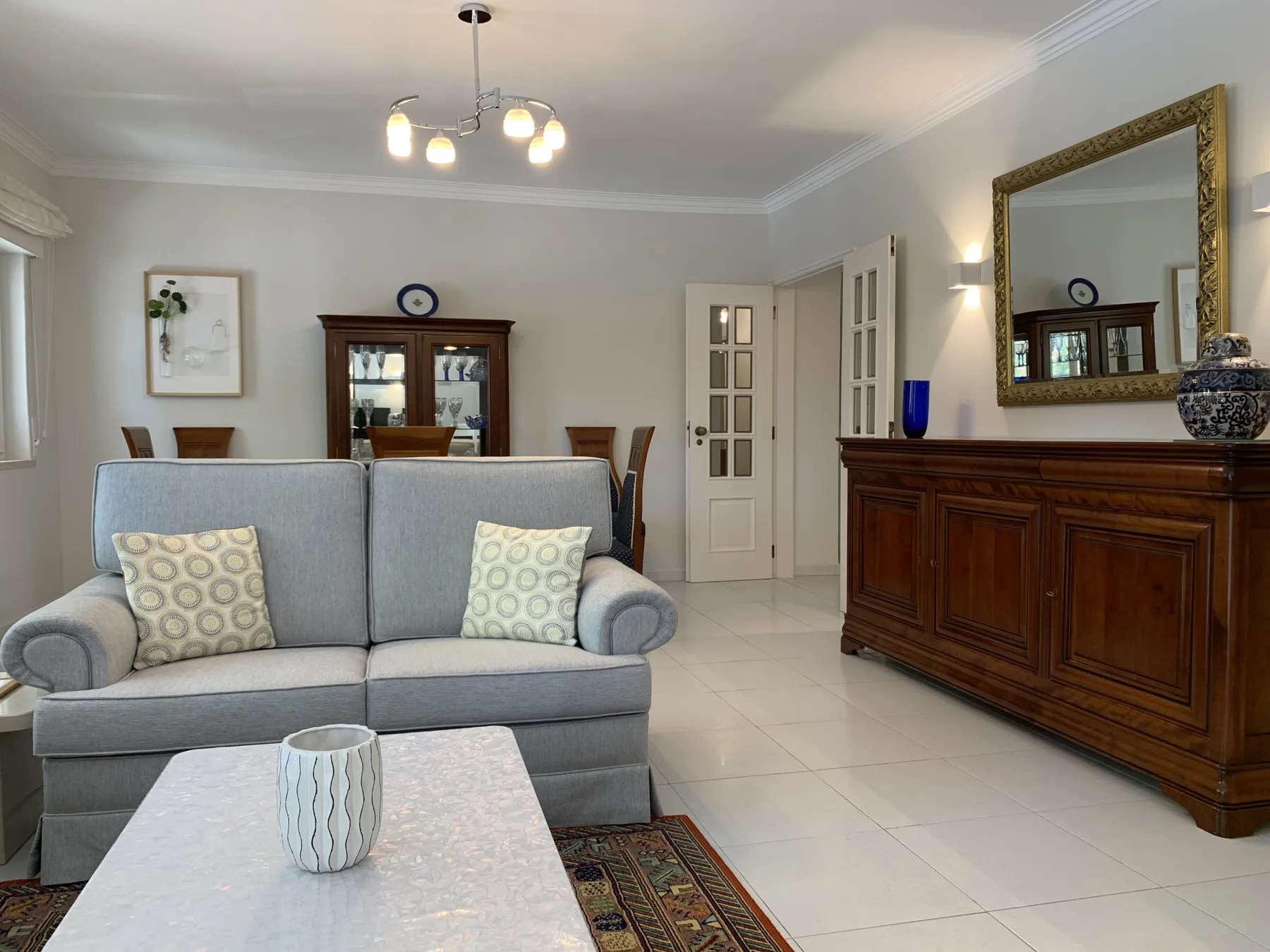 Una sala de estar con un sofá gris, una mesa de centro y un aparador de madera.