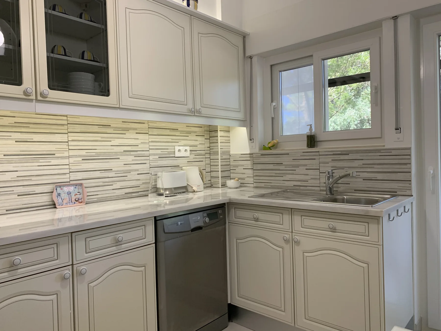 Una cocina luminosa con gabinetes claros, una encimera y un fregadero bajo una ventana.
