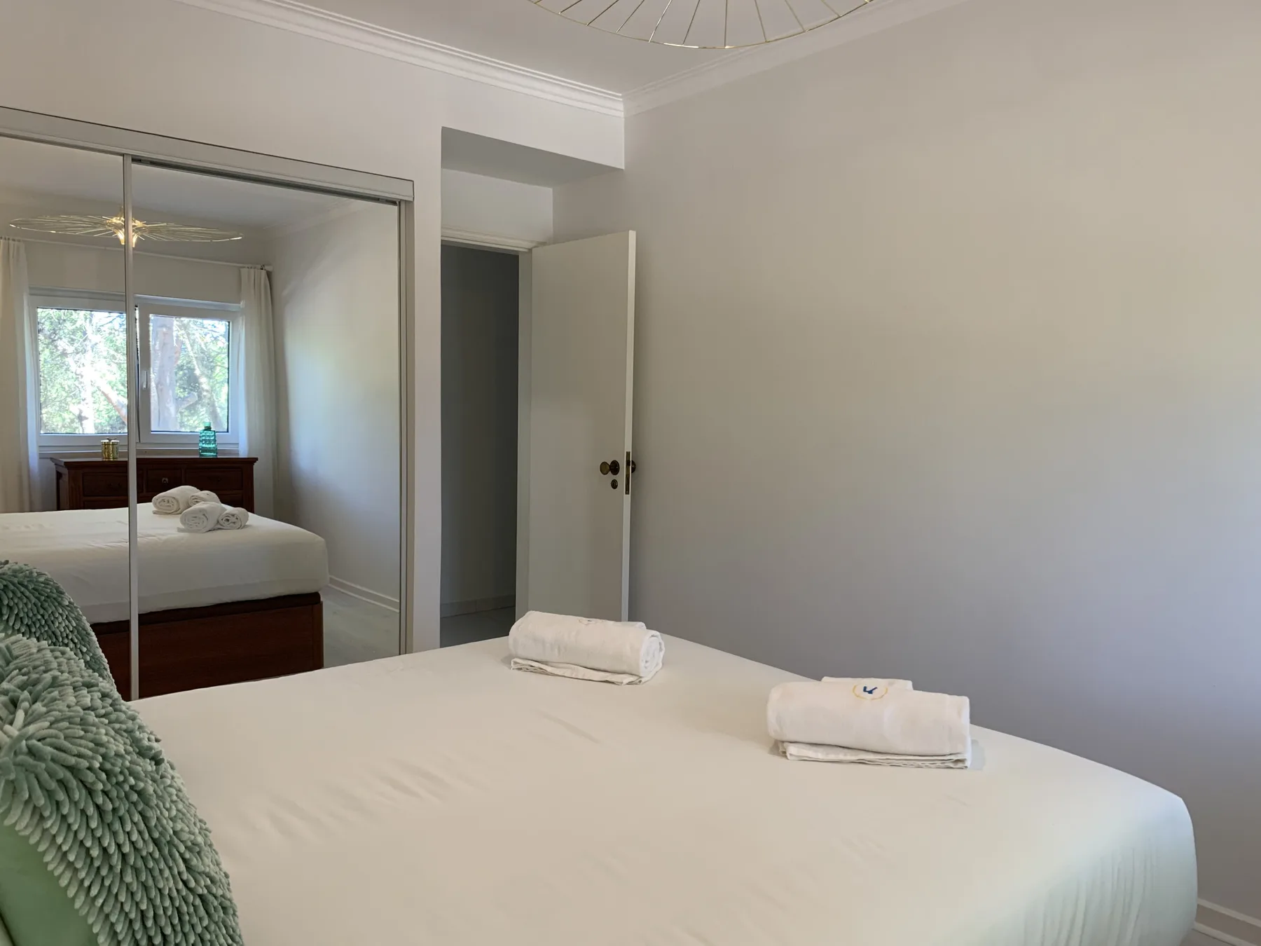 Un dormitorio luminoso con una cama grande y puertas de armario con espejo.