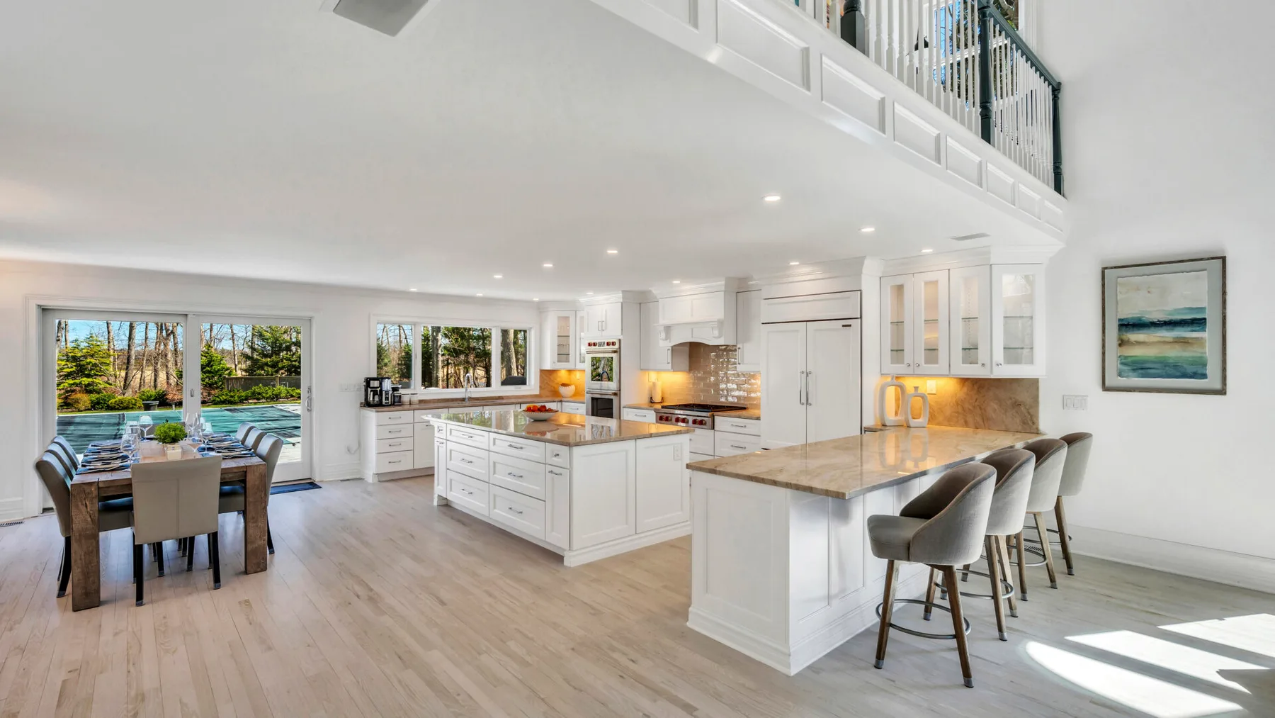 A bright open-plan kitchen and dining area features a central island and large windows.