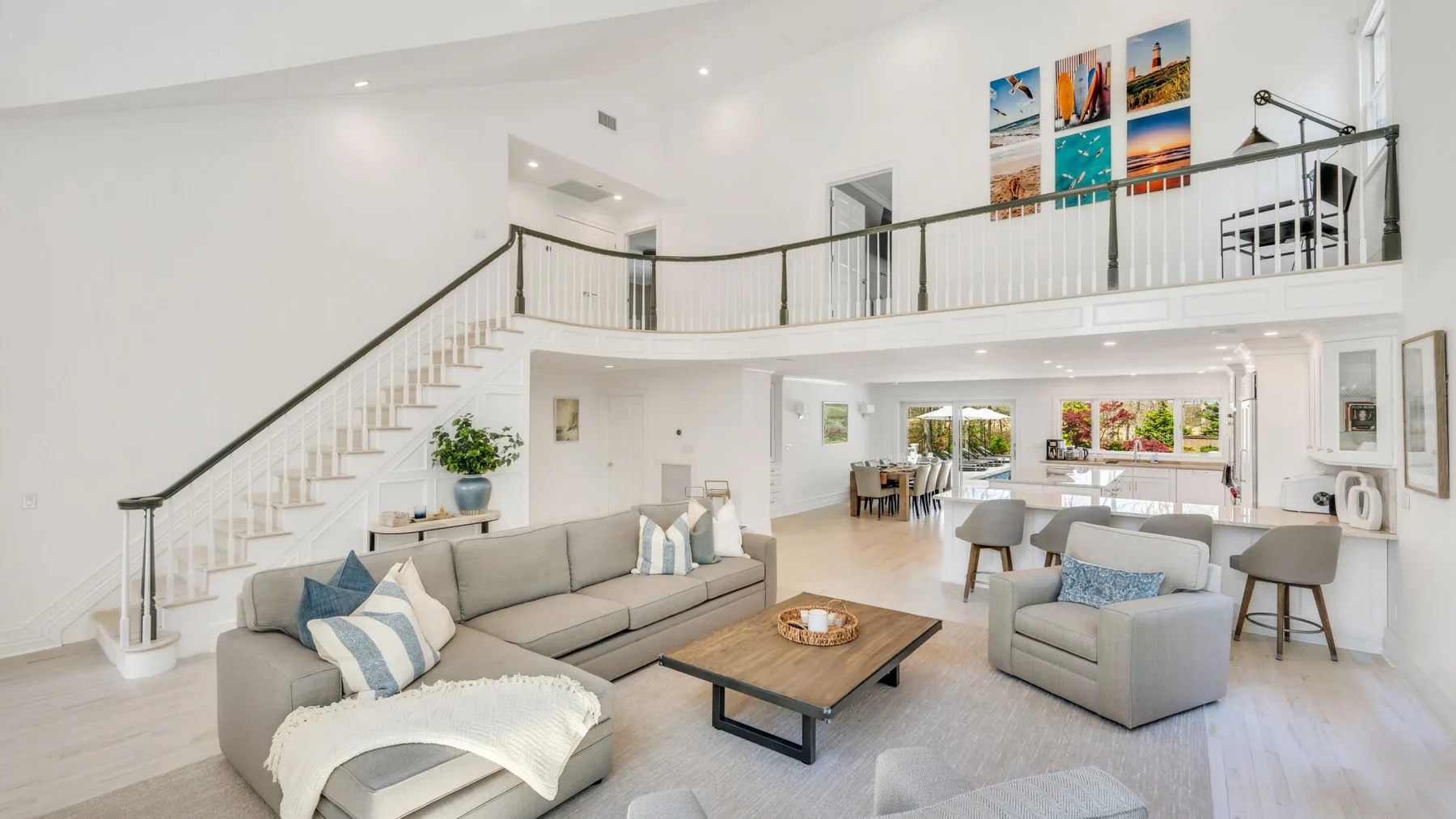 A bright open-plan living area with seating beneath a mezzanine and staircase.