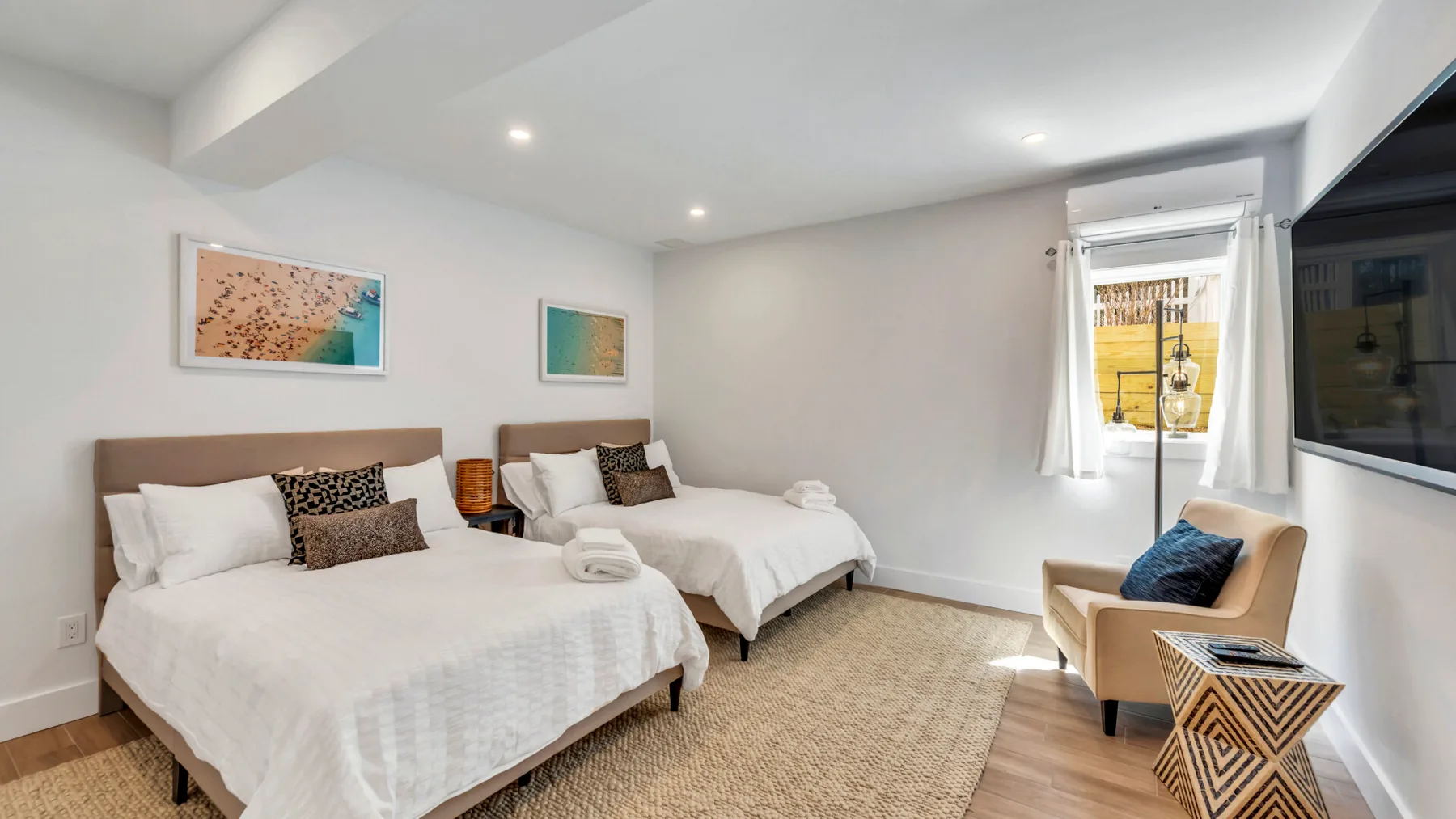 A bright bedroom with two beds and a seating area beside the window.
