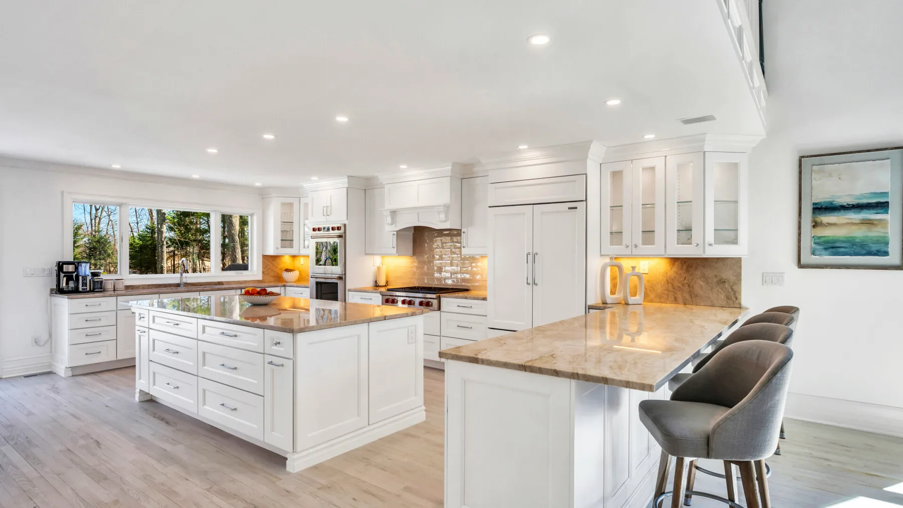 A bright kitchen with white cabinetry, stone countertops, and a central island.