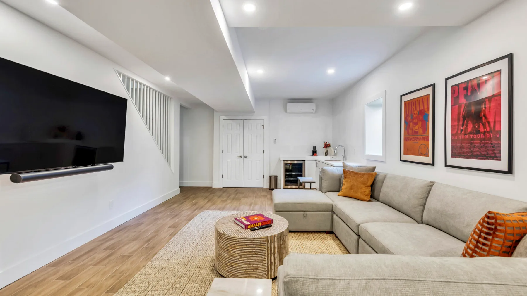 A bright living room with a large sectional seating area and wall-mounted television.