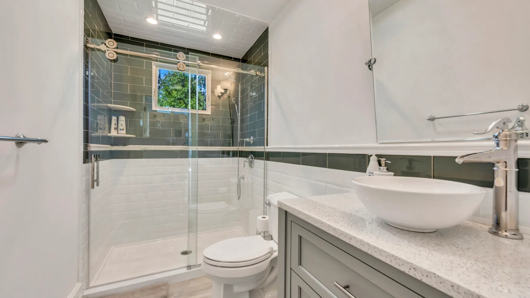 A modern bathroom with a glass shower and a sink vanity.